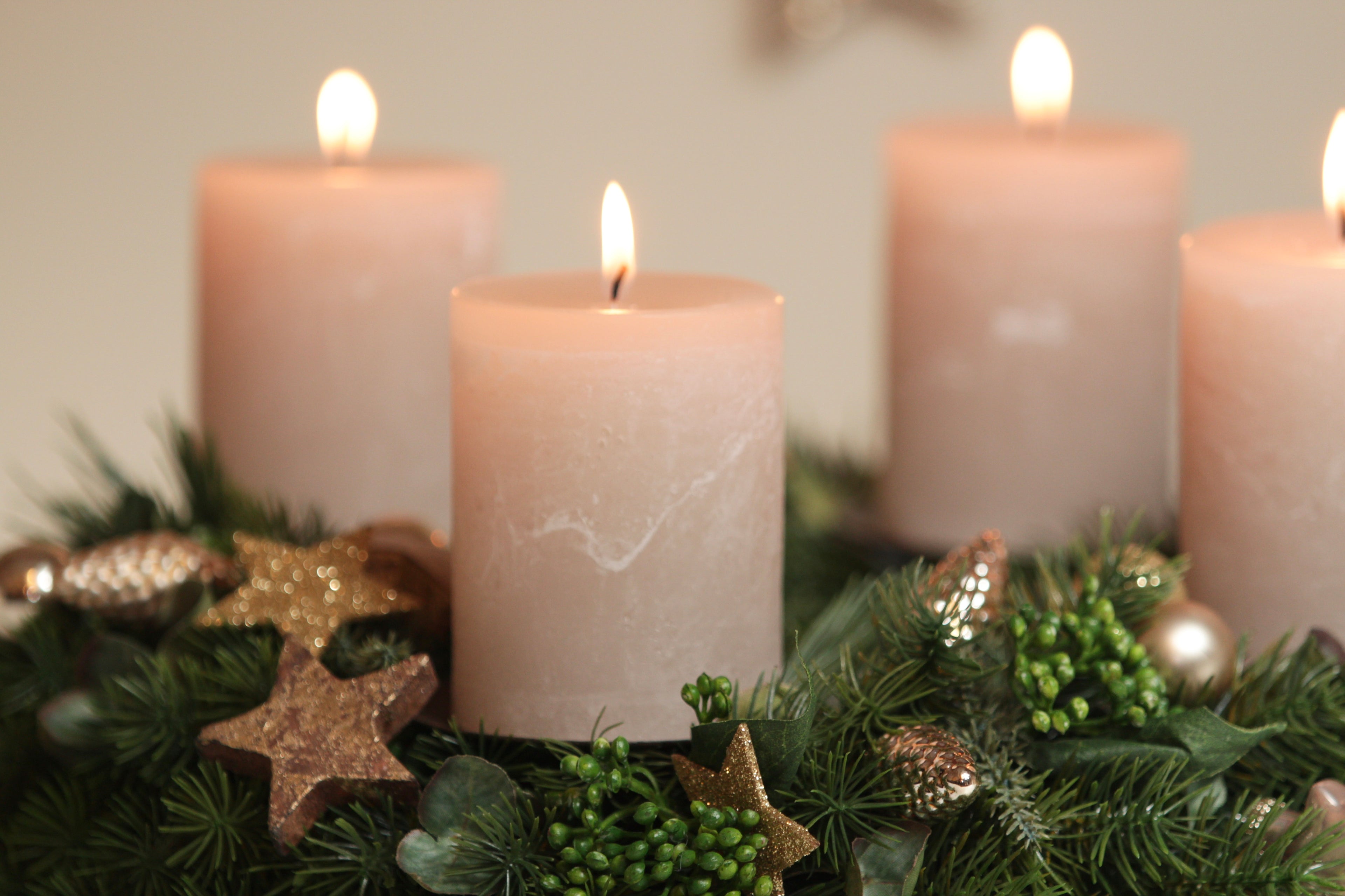 Adventskranz mit vier brennenden Stumpenkerzen und festlicher Weihnachtsdeko