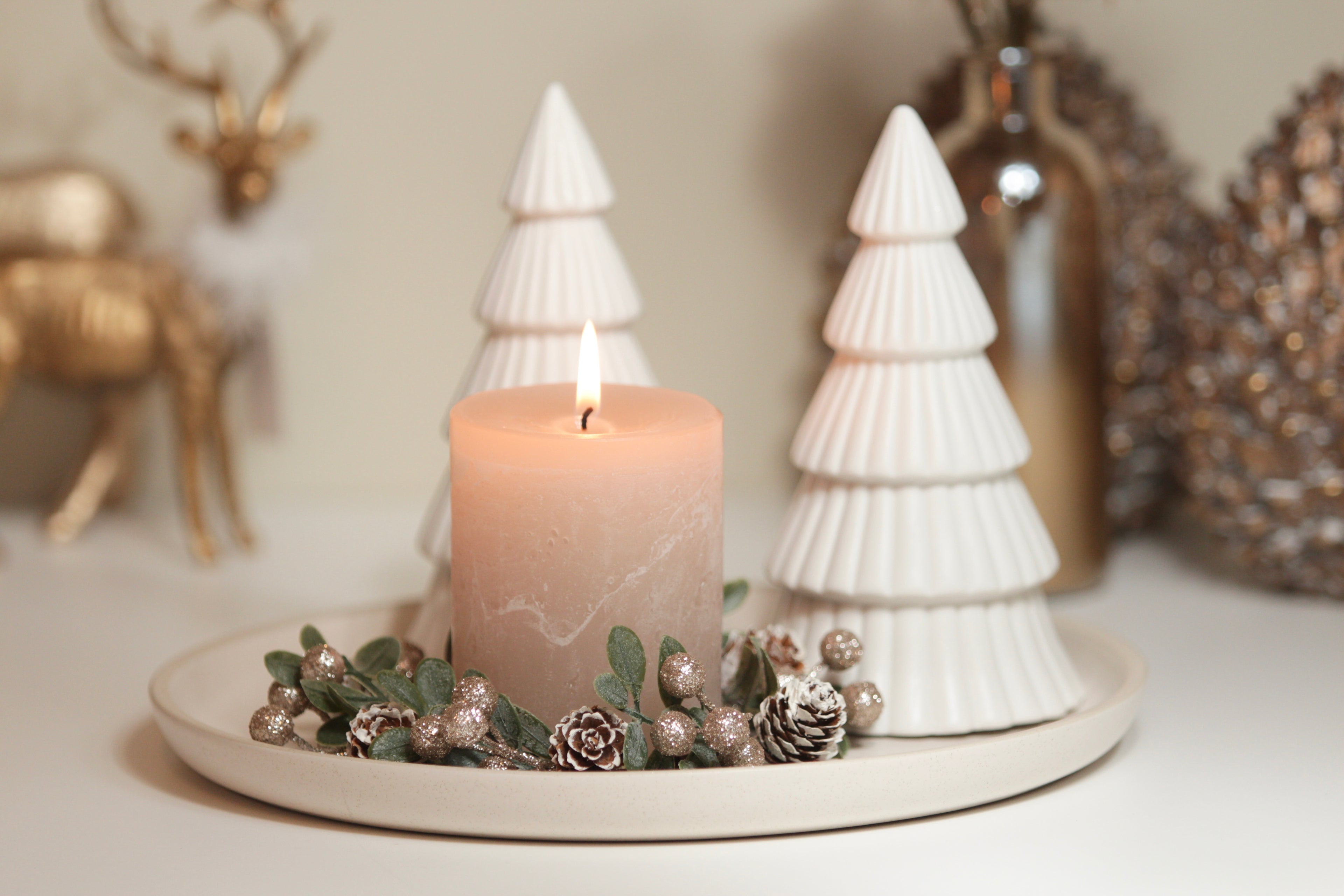 Stilvolle Weihnachtsdeko mit beiger Stumpenkerze und weißen Deko-Tannenbäumen