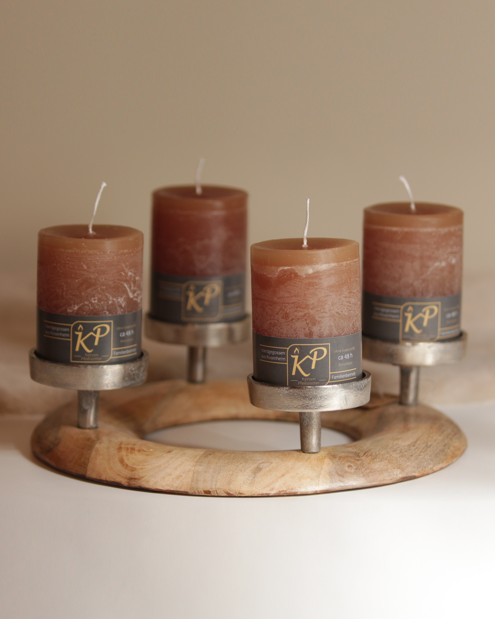 Runder Adventskranz aus Holz mit silbernen Kerzenhaltern und vier karamellfarbenen Kerzen.