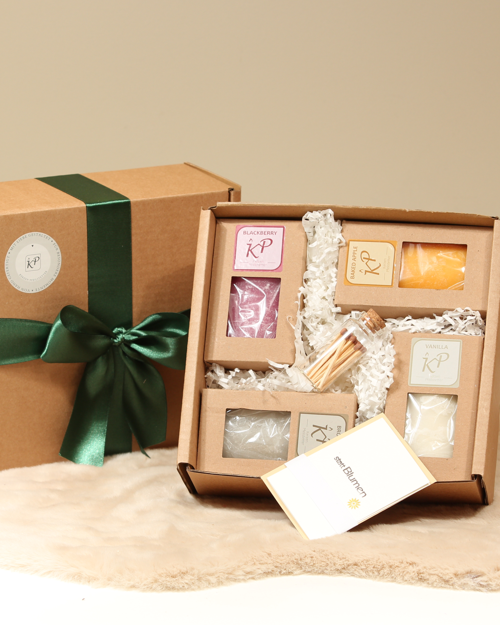 Geschenkbox mit vier handgegossenen Duftkerzen – Vanilla, Blackberry, Brownie, Baked Apple – mit Streichhölzern und Karte, verpackt mit grünem Satinband