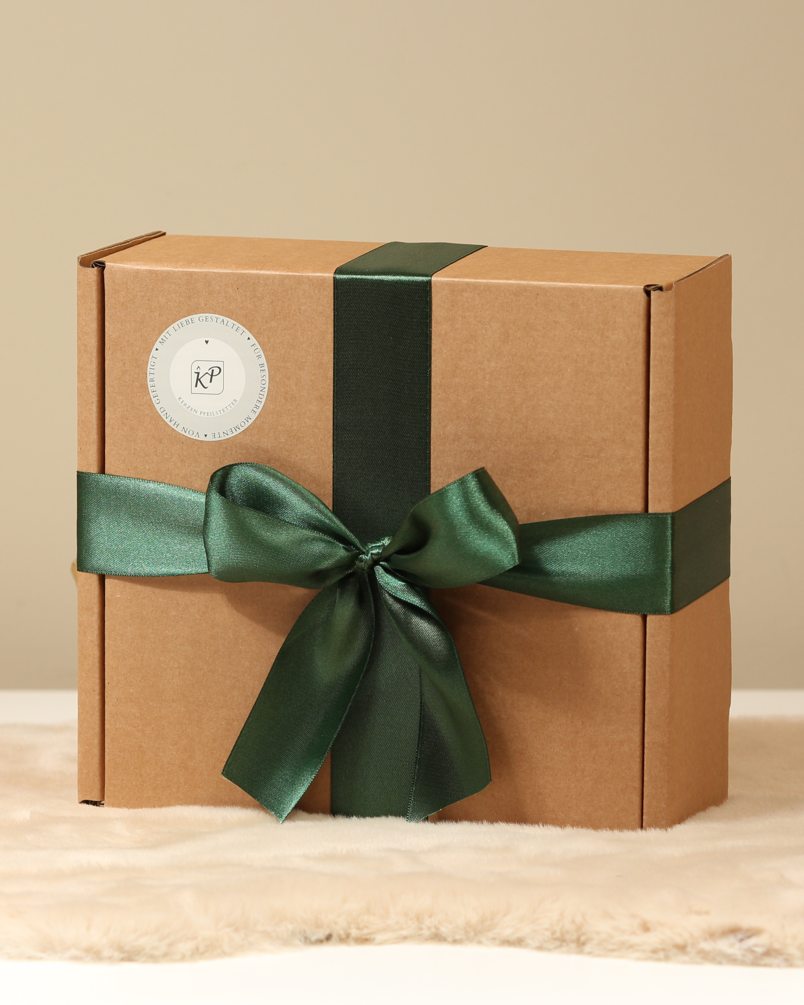 Nachhaltig verpackte Geschenkbox mit grünem Satinband – Kerzen Pfeilstetter