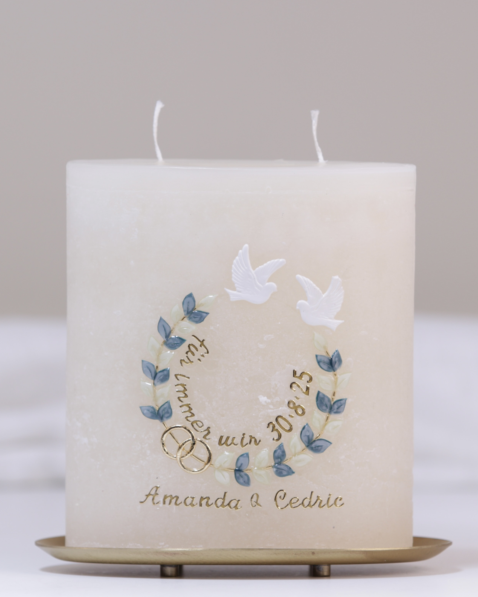 Handgefertigte Hochzeitskerze mit zwei goldenen Herzen, Tauben, Blumenranke und dem Spruch „für immer wir“ in Cremefarbe.