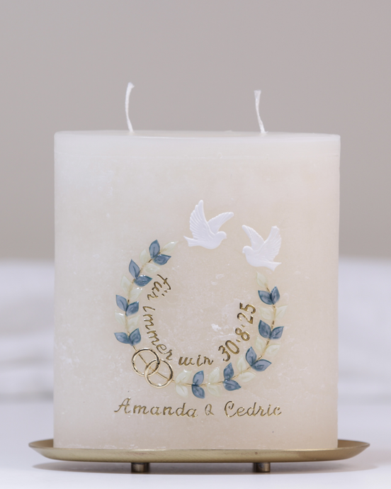 Handgefertigte Hochzeitskerze mit zwei goldenen Herzen, Tauben, Blumenranke und dem Spruch „für immer wir“ in Cremefarbe.