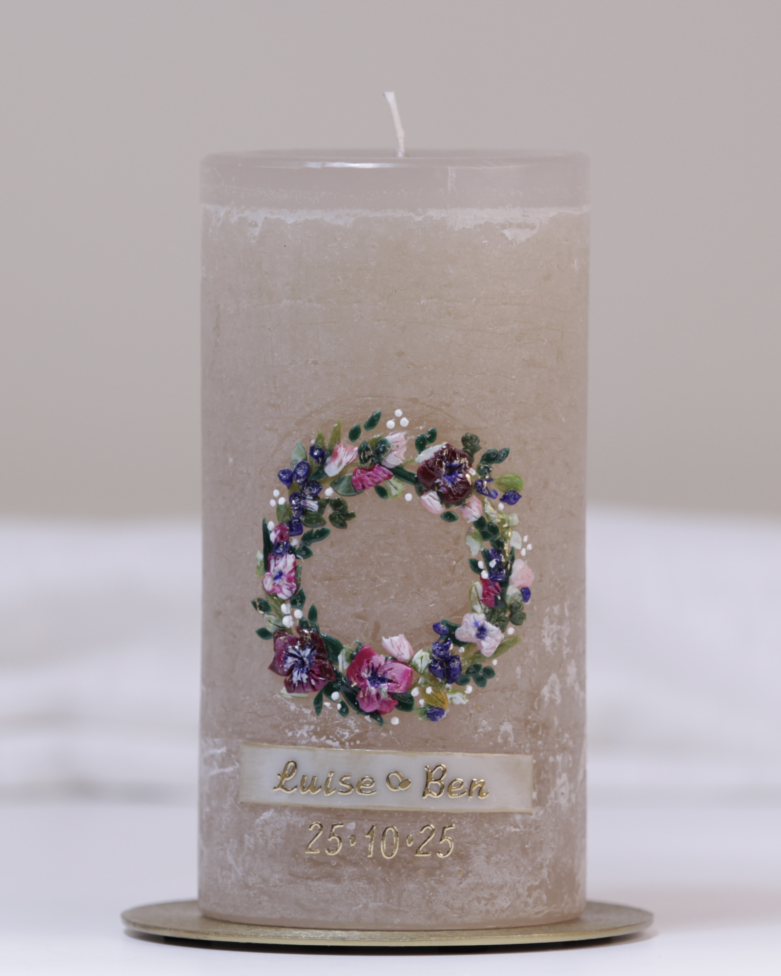 Sandgraue Hochzeitskerze mit farbenfrohem Blumenkranz – kunstvoll handverziert für den besonderen Tag.