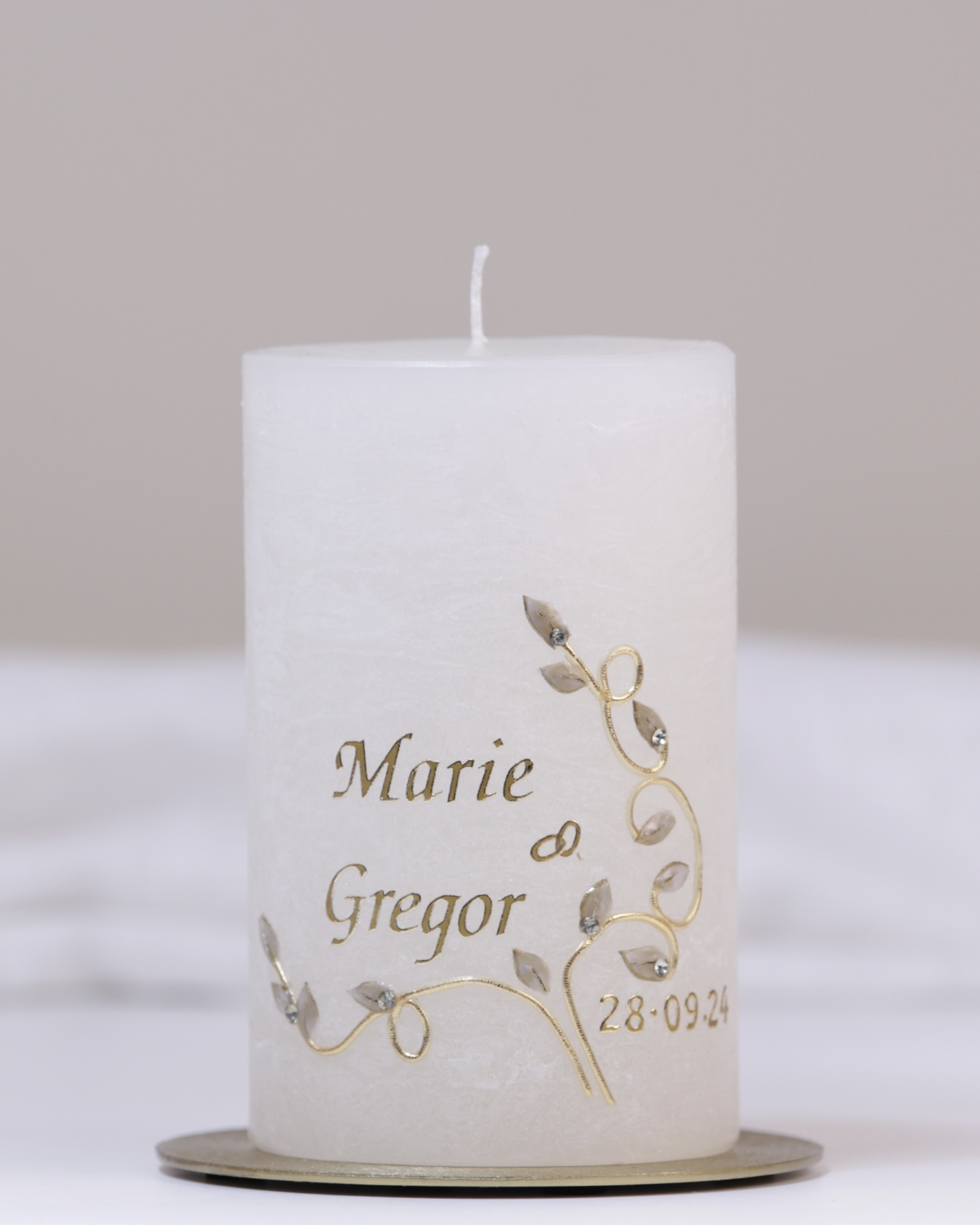 Elfenbeinfarbene Hochzeitskerze mit geschwungener goldener Blumenranke, Eheringen und funkelnden Strassteinchen.