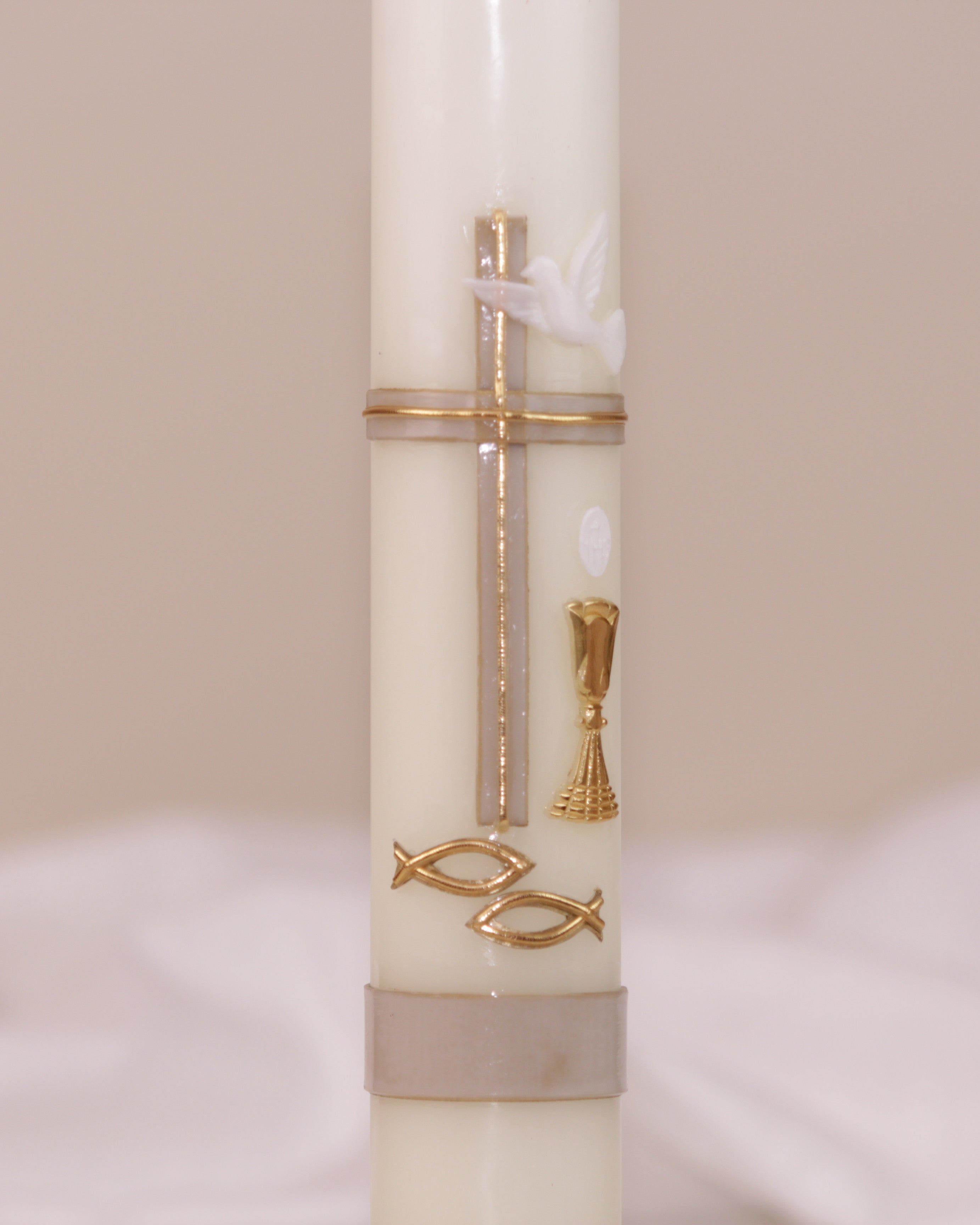 Detailansicht der goldfarbenen Verzierung mit Kreuz, Taube, Kelch und zwei Fischsymbolen – traditionell verziert auf Kommunionskerze von Wiedemann.