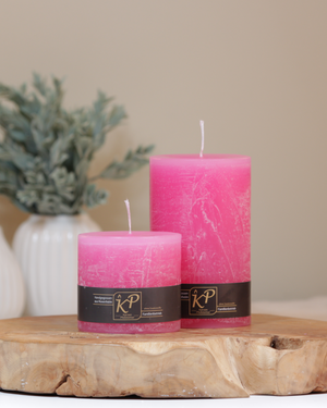 Stumpenkerzen in pink in zwei Größen – dekorativ auf einem Holztisch mit Pflanze im Hintergrund.