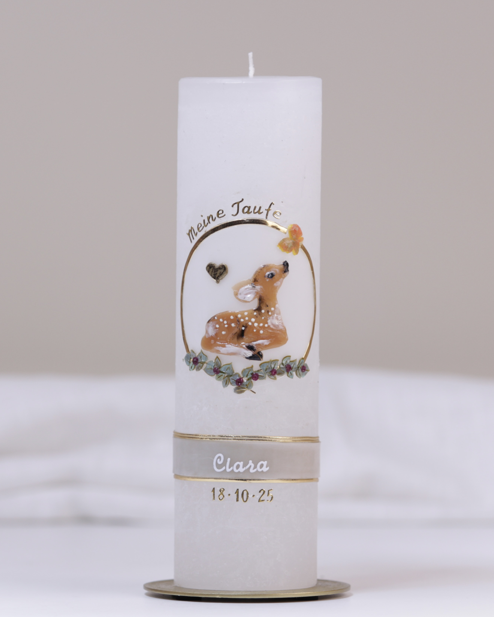 Weiße Taufkerze mit lila-goldener Verzierung aus handgeformtem Rehkitz, Blumenranke, Kreuz und Schmetterling.