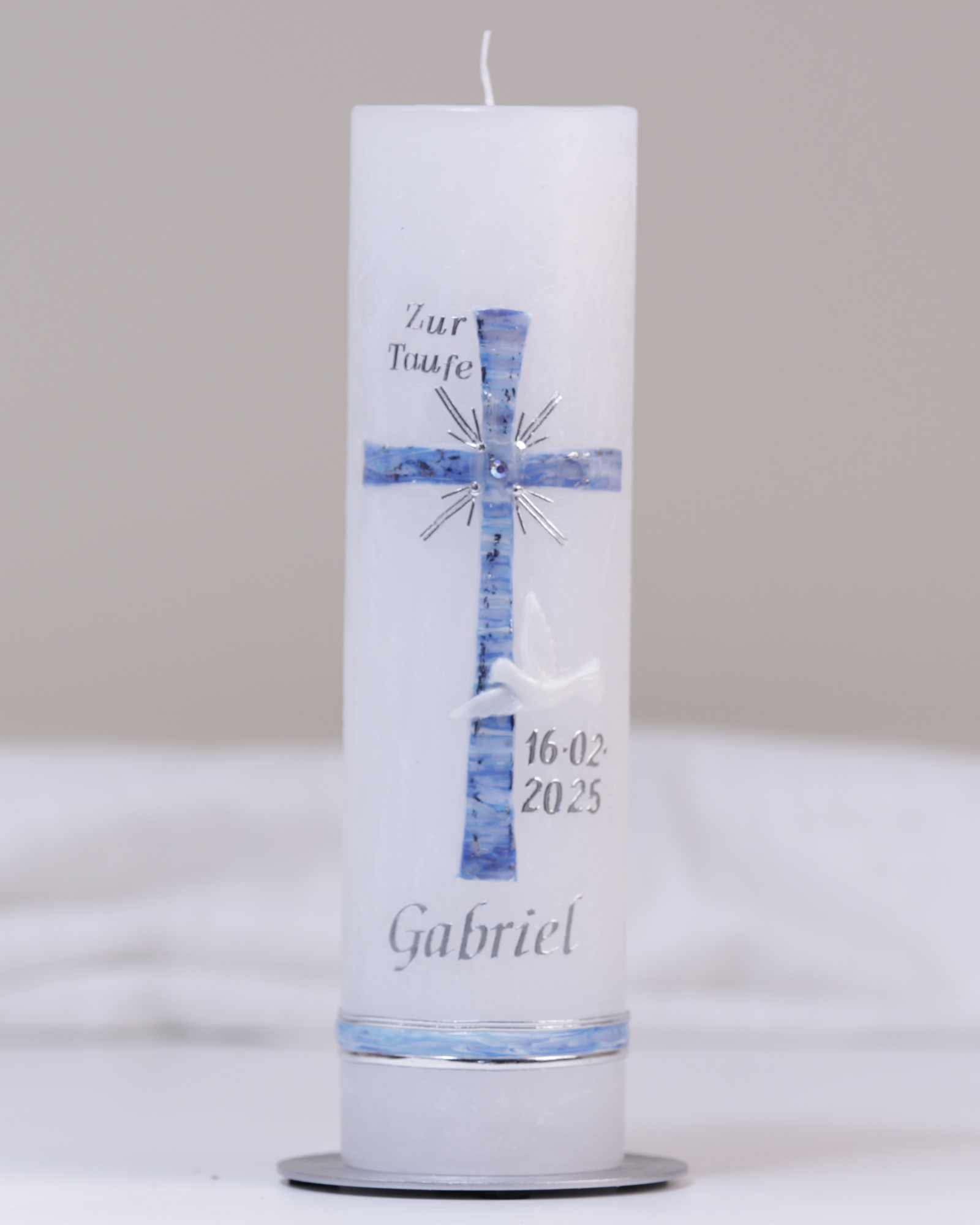 Weiße Taufkerze mit silber-blauer Verzierung aus Kreuz, Taube und „Zur Taufe“-Schriftzug.