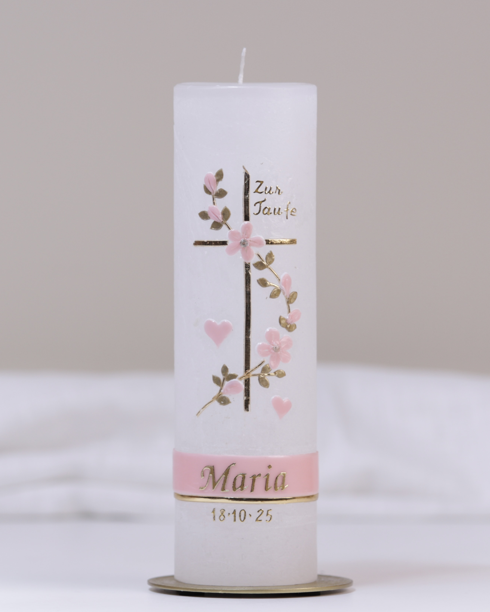 Weiße Taufkerze mit rosa-goldener Verzierung aus Kreuz, Herz, Blumenranke und „Meine Taufe“-Schriftzug.