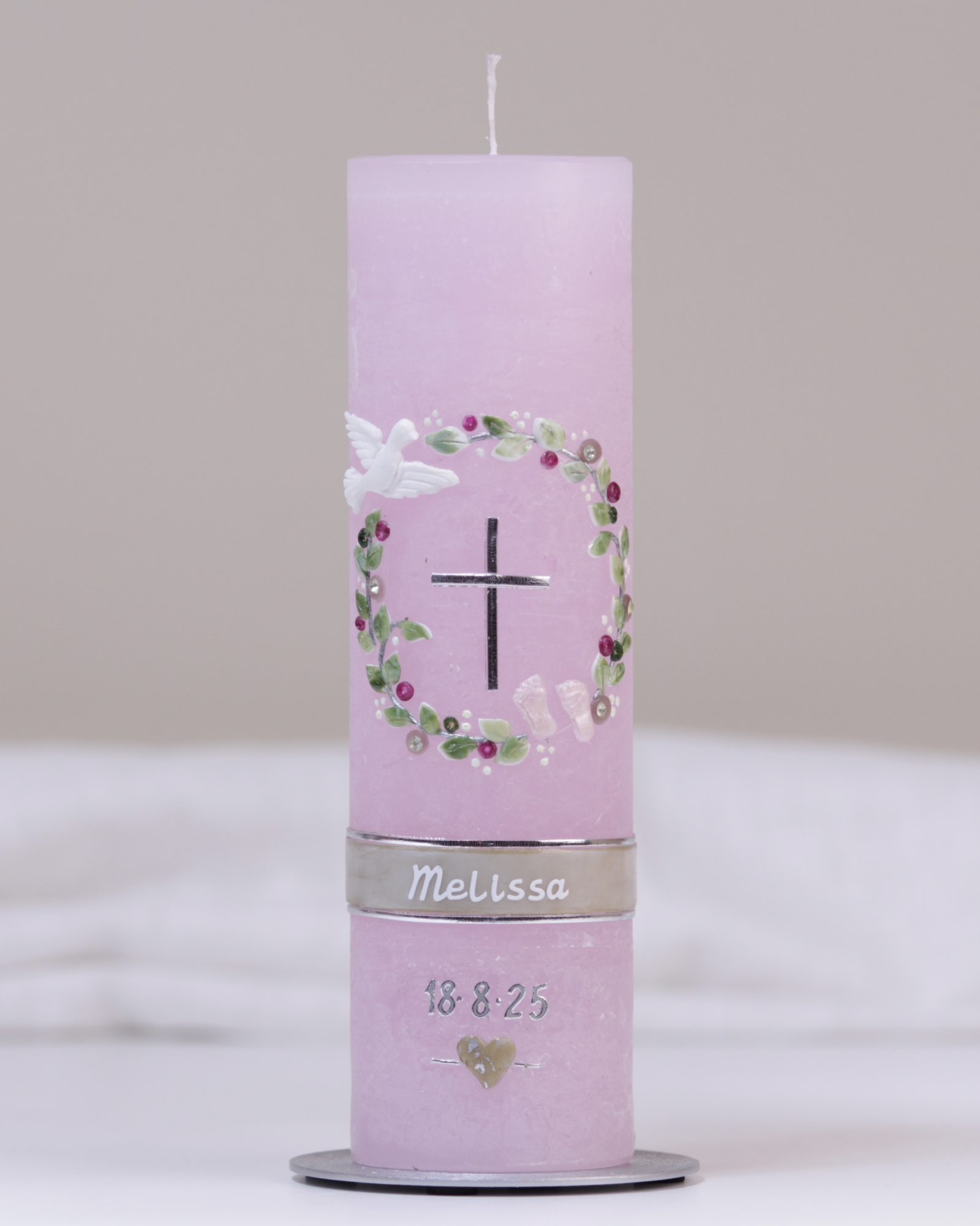 Pastellrosa Taufkerze mit silber-rosafarbener Verzierung aus Kreuz, Blumenkranz, Taube und Füßchen.
