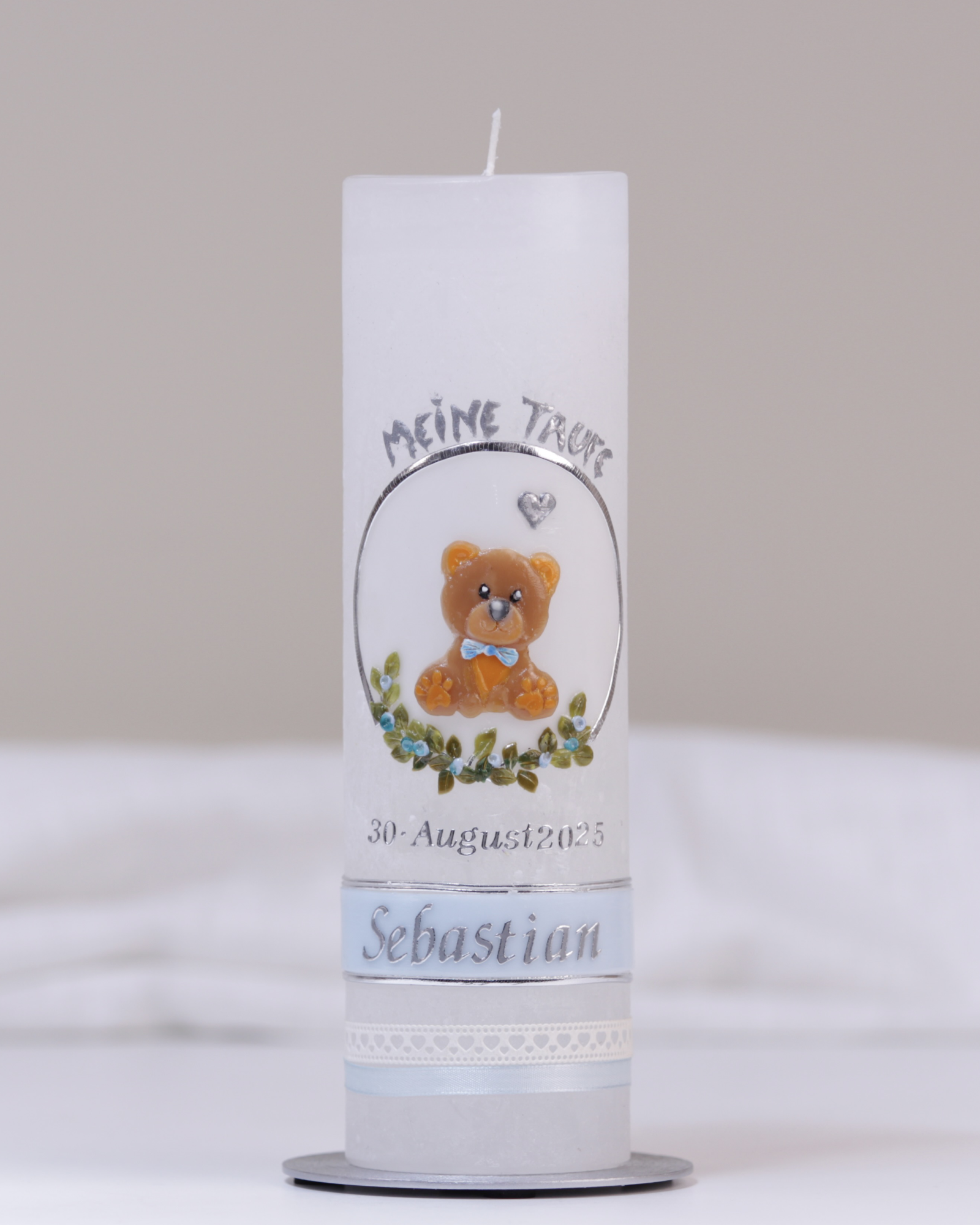Weiße Taufkerze mit silber-blauer Verzierung aus handgeformtem Bärchen, Kreuz, Herzchen und Blumenranke.